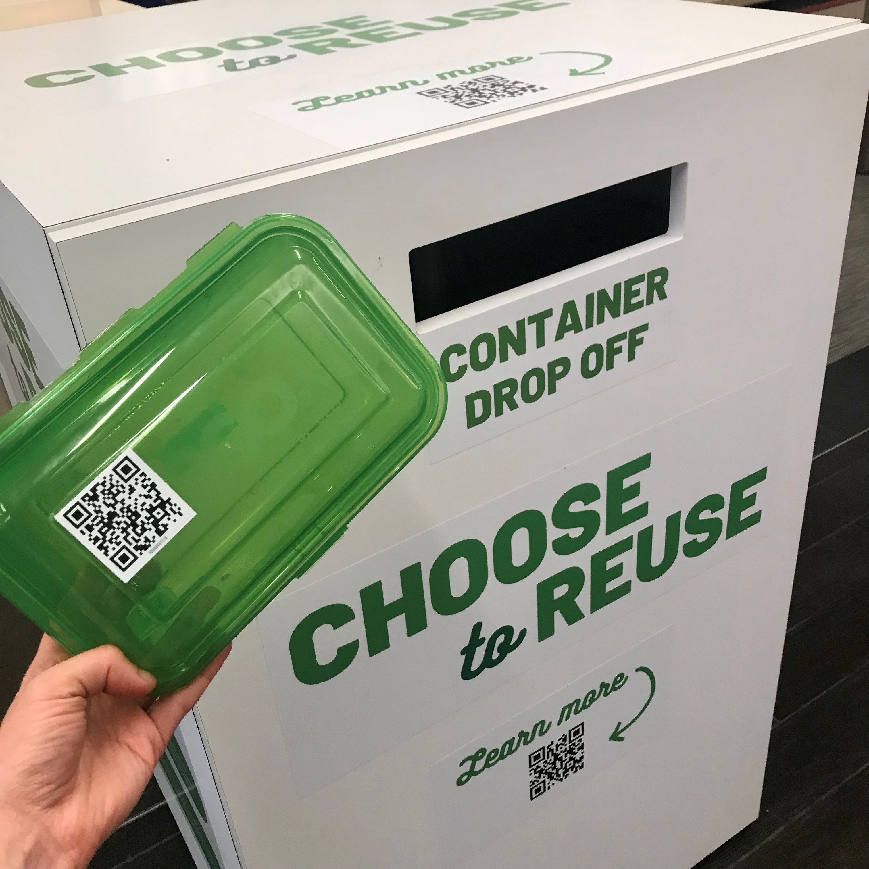 Returning a reusable food container with a scannable QR code to a Choose to Reuse container drop off box.